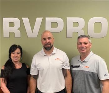 three posing in front of SERVPRO signage