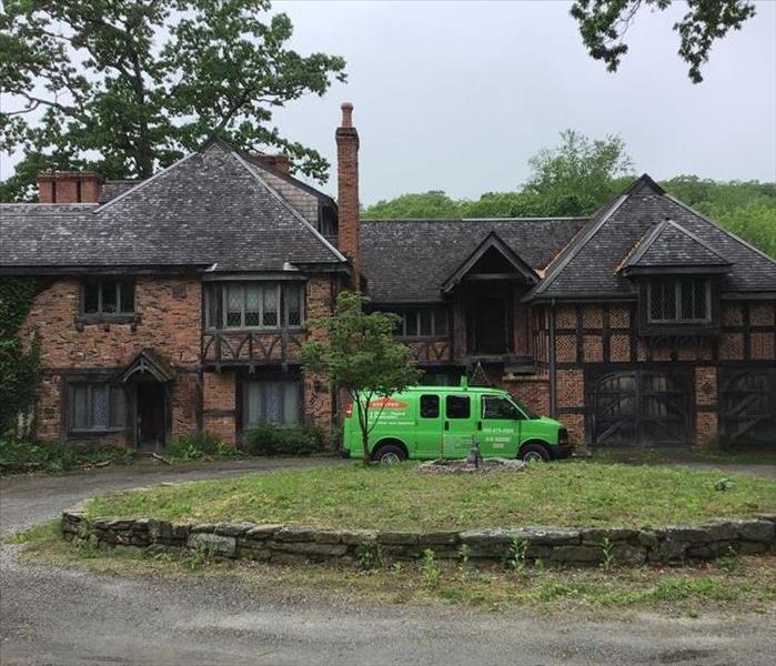 van parked in circular driveway of large house